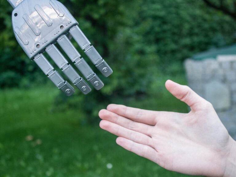 Ein Roboter gibt einem Menschen die Hand. Kann KI oder Roboter in naher Zukunft in der Pflege aushelfen?