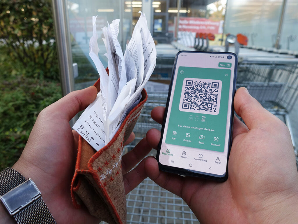 Smartphone mit QR-Code und Kassenbelege.
