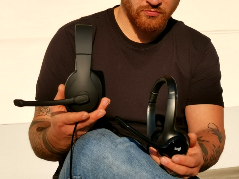 Mann hält in beiden Händen Headsets die im Vergleich stehen