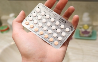 A hand holding birth control pills.