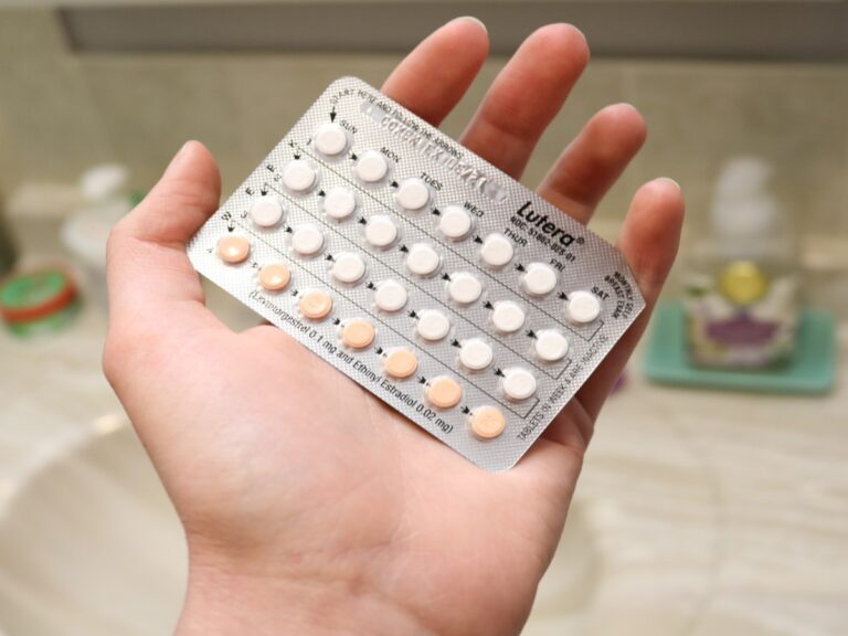A hand holding birth control pills.