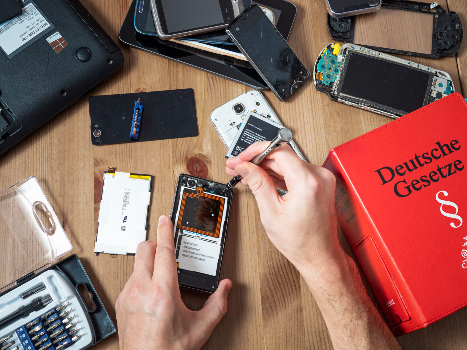 Top-Down Sicht auf Handyreparatur umgeben von kaputten Elektrogeräten