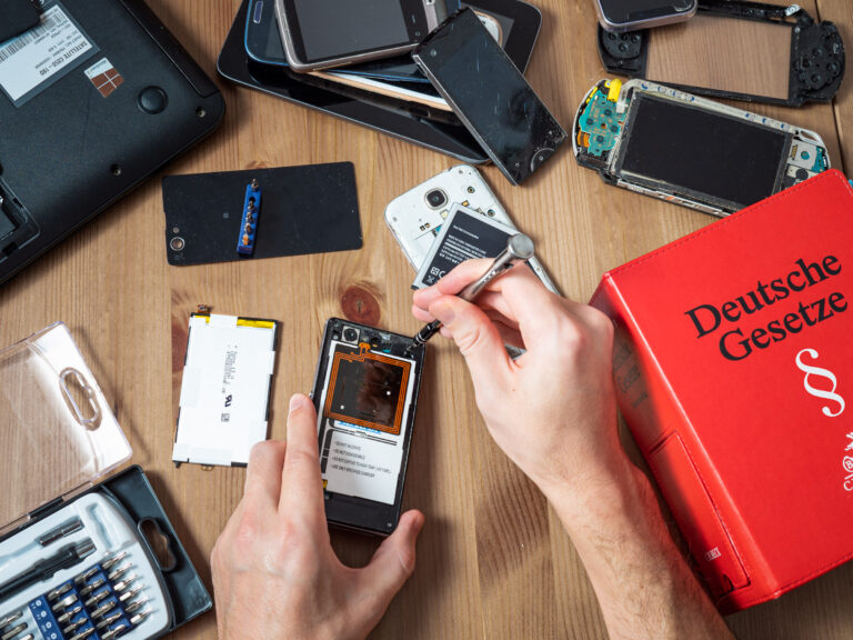Top-Down Sicht auf Handyreparatur umgeben von kaputten Elektrogeräten