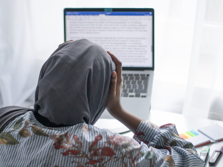 Ratlose Studentin sitzend vor dem Laptop.